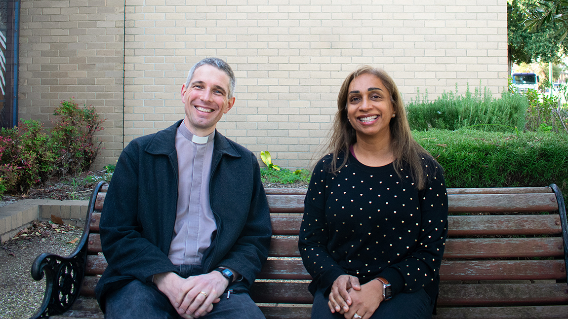 Chaplain and pastor sitting and smiling together on a bench outside